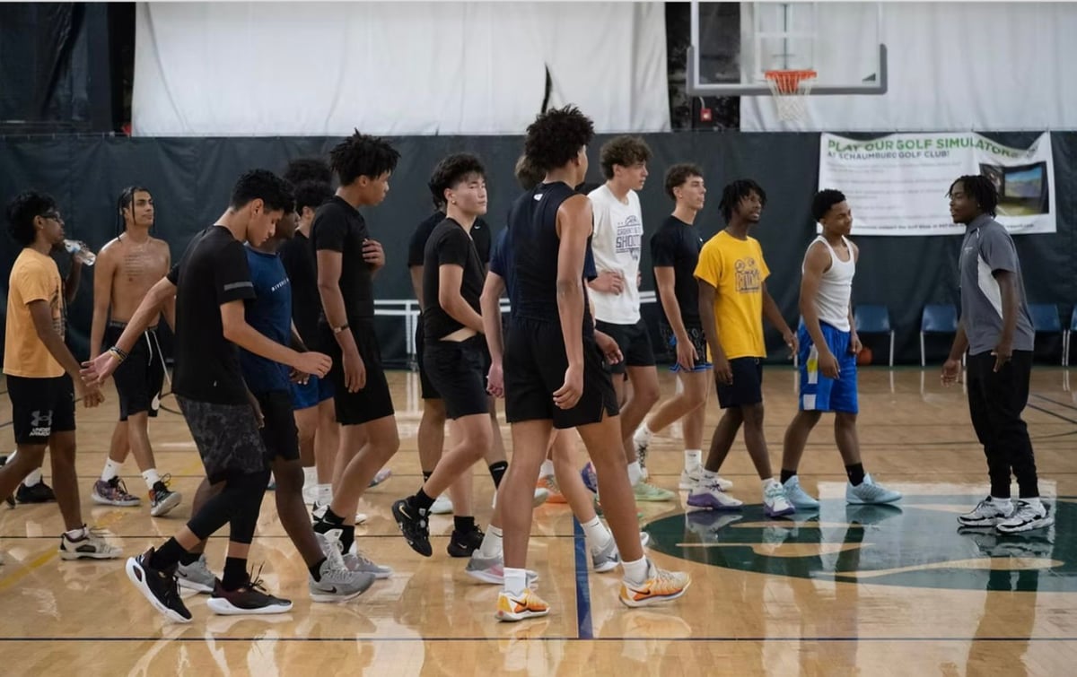 Group of young athletes gathered in a gymnasium, standing on a basketball court for what appears to be a team practice or training session