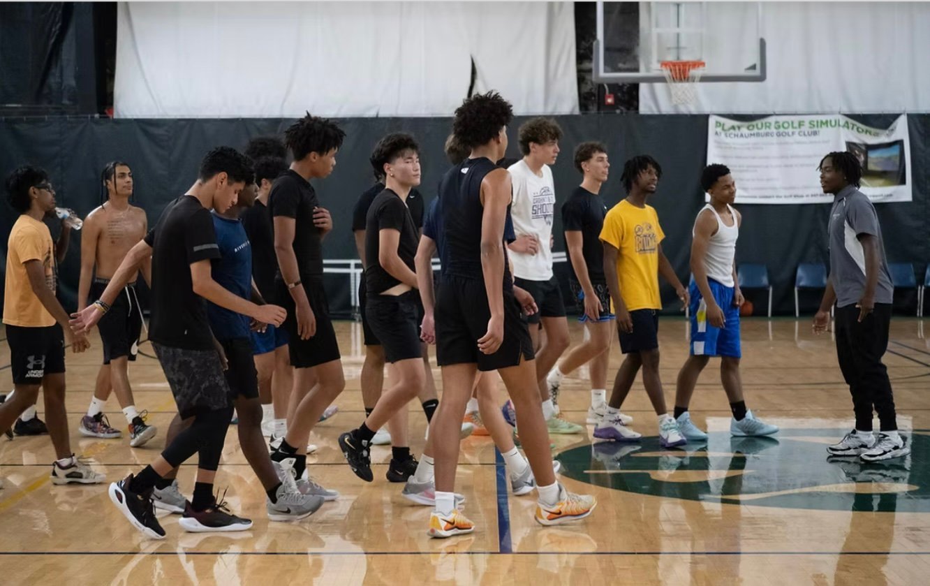Group of young athletes gathered together on an indoor gymnasium basketball court during a practice or training session