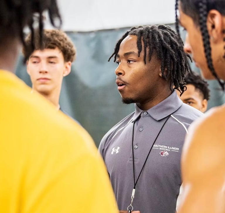 Coach in gray shirt speaking to athletes in yellow shirts during team gathering outdoors